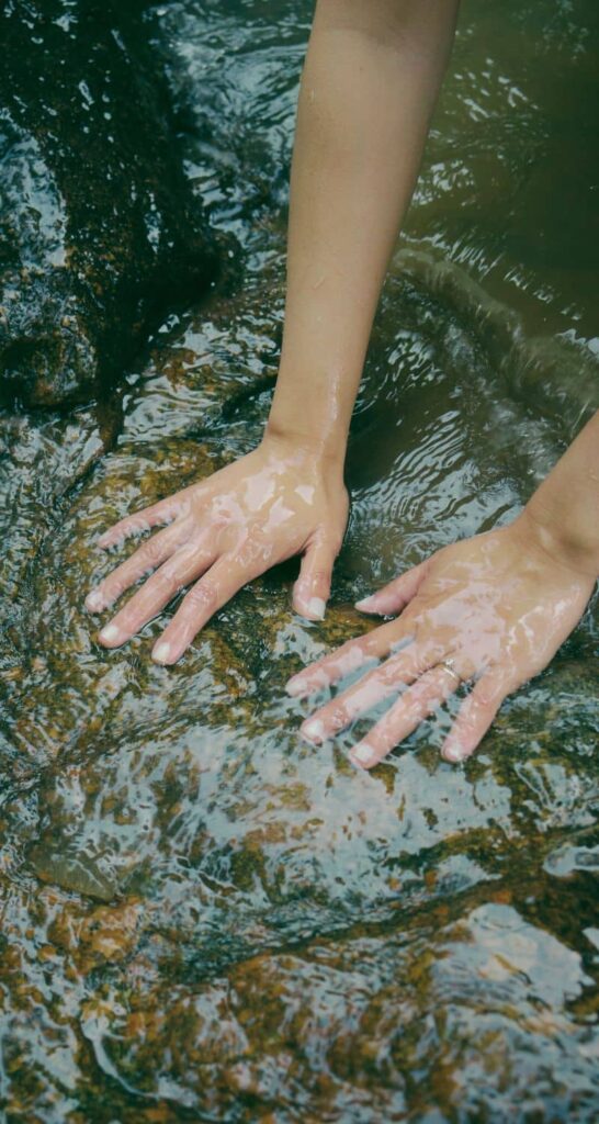 Frau hat ihre Hände in Wasser, sie will sich mit Hilfe ätherischer Öle weiterentwickeln und schätzt die Natürlichkeit.