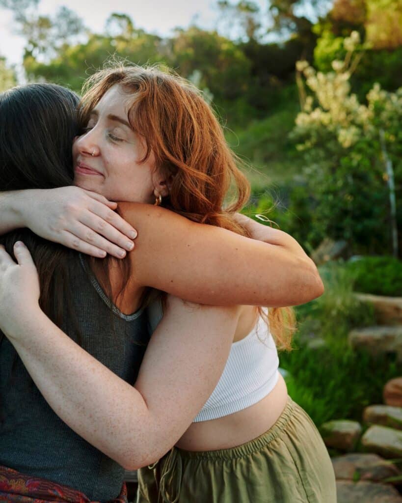 Eine Frau umarmt eine andere Person, Symbol für Verbindung und Harmonie – ein Moment, der zeigt, wie man regenerativ leben kann.